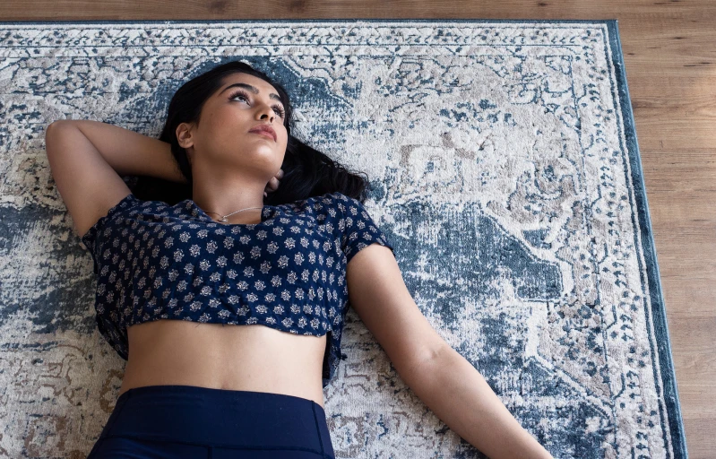 a young woman lying on top of a blue rug