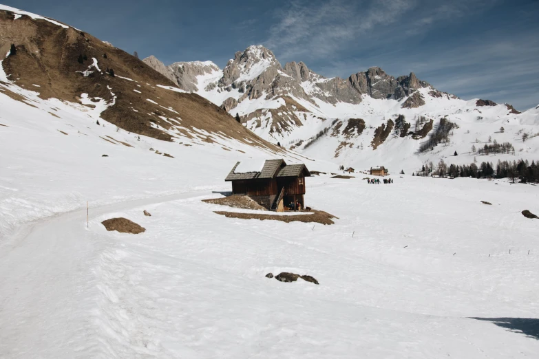 a snow covered mountain range with a small cabin near by