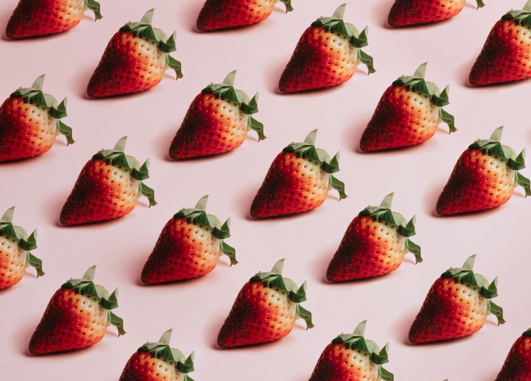 many strawberries arranged on a light pink background