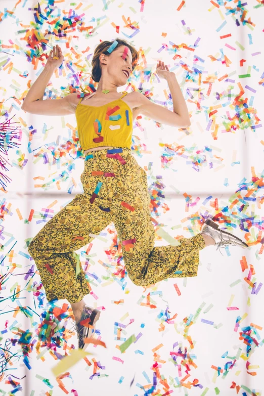 a young woman jumping through a bunch of confetti