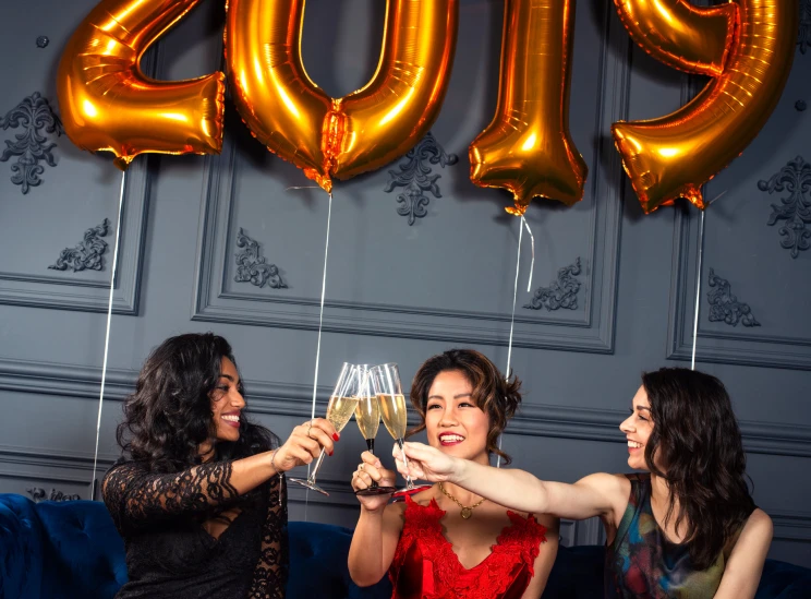 three women toasting and holding glasses with the word cheers