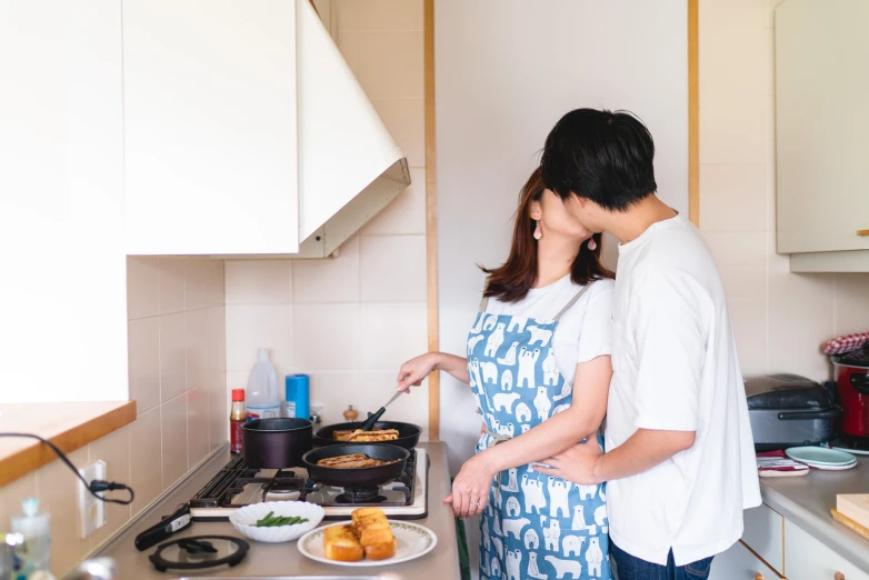 a couple who are standing near the stove