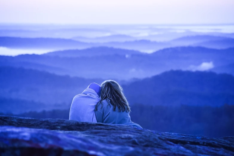 the woman is sitting on the top of a mountain looking at the horizon