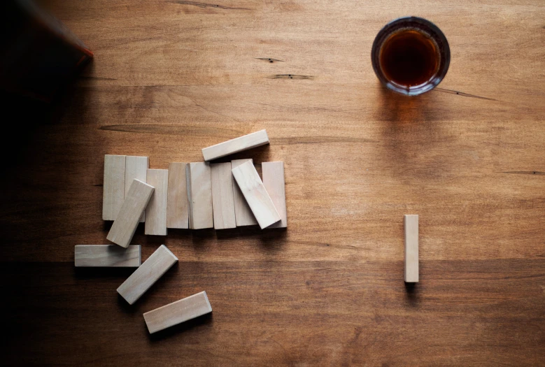 a wooden type of domino board next to a cup with soing inside it