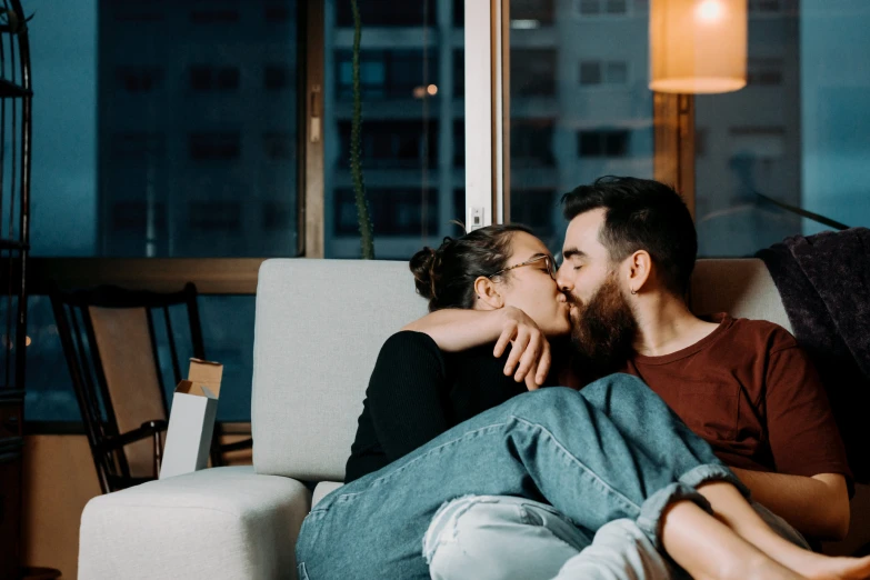 a man sitting on the couch kisses a woman on her forehead