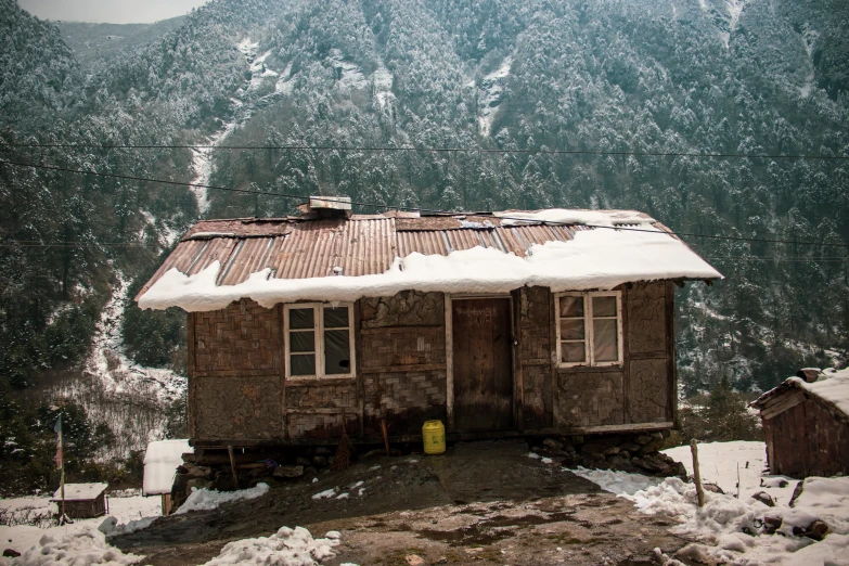 a small wooden building near a snow covered mountain