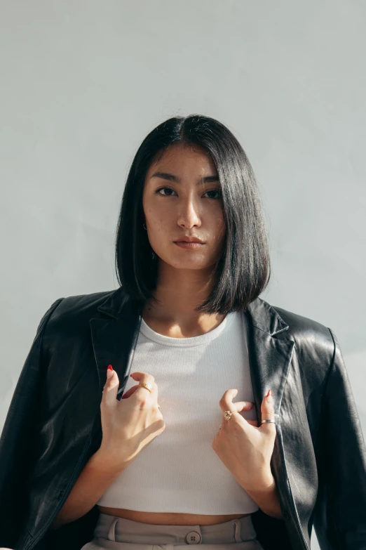 a woman in white shirt and black jacket looking at the camera