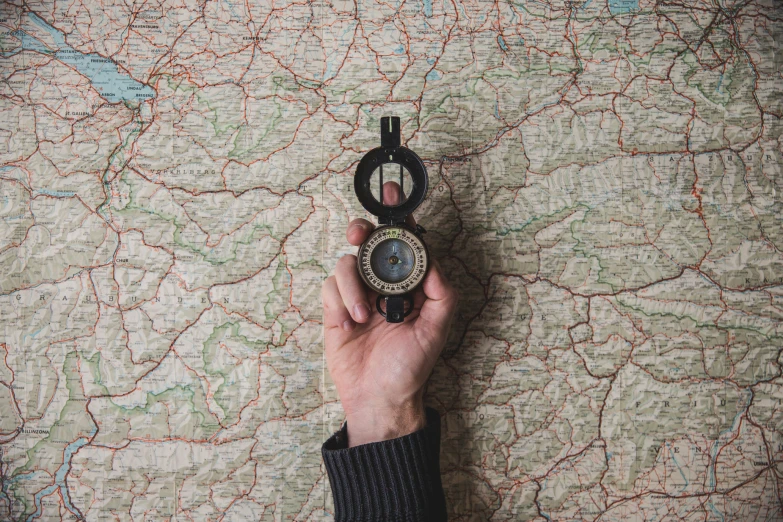 a hand holding a compass near a map