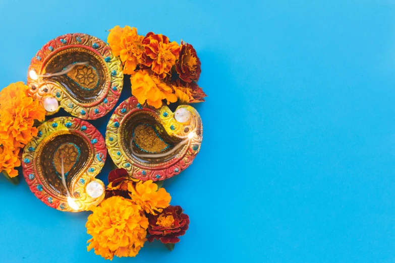 decorated dishes of flowers and orange candles with a blue background