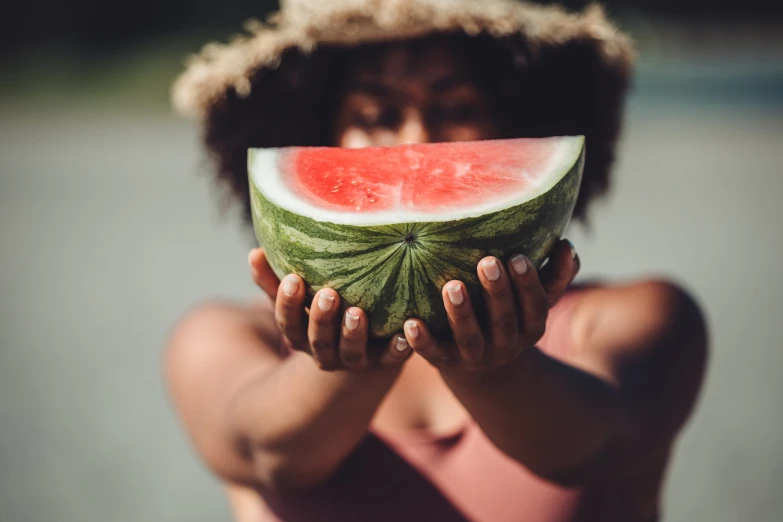 a woman is holding up a slice of watermelon