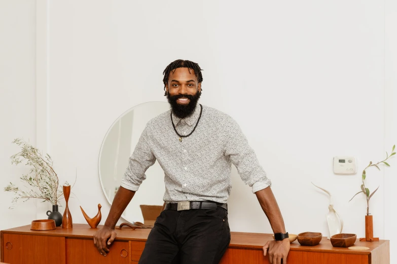 a man sitting on a dresser next to a large mirror