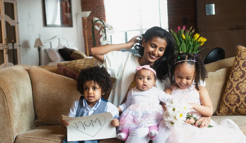 a woman posing with her three children and holding a heart