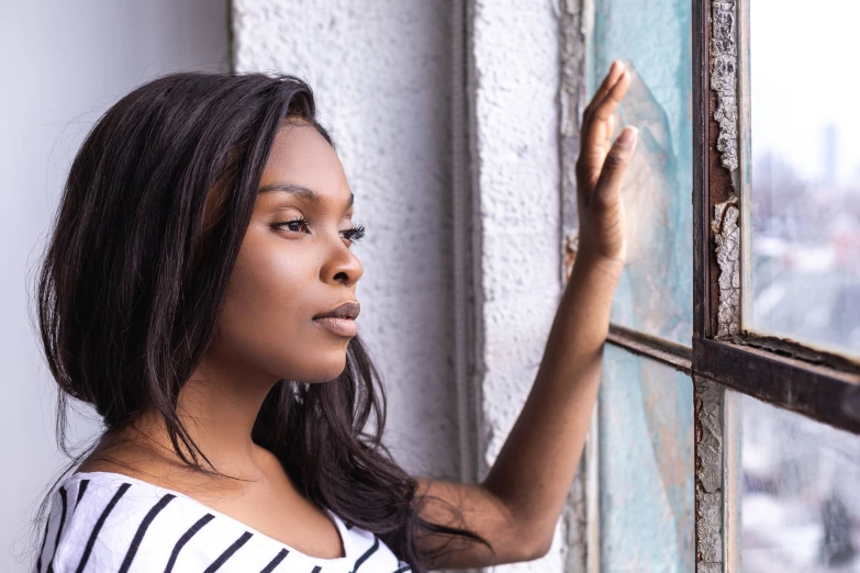 a young woman leans on a window sill as she points out a building's window