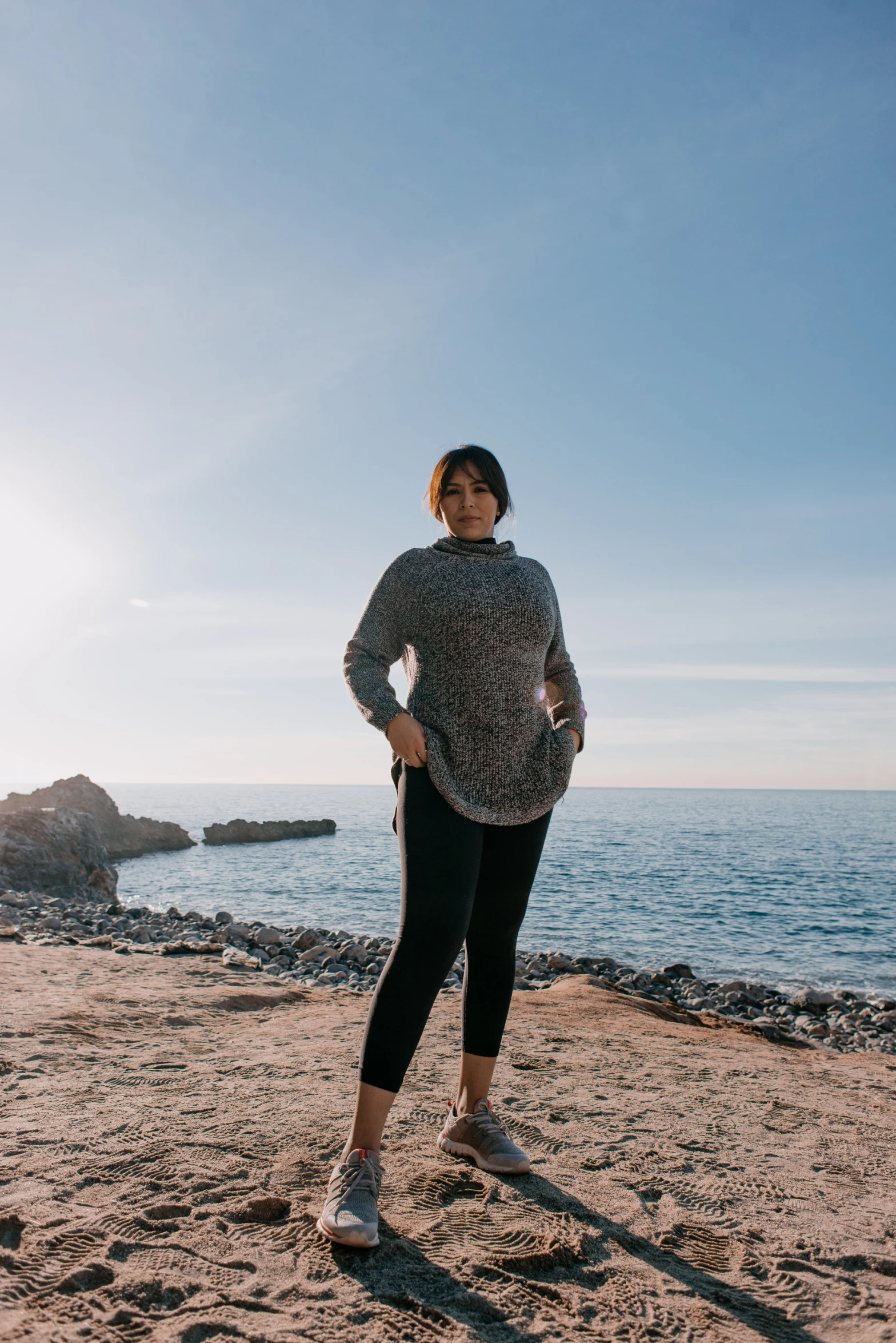 a woman in all black standing on a beach