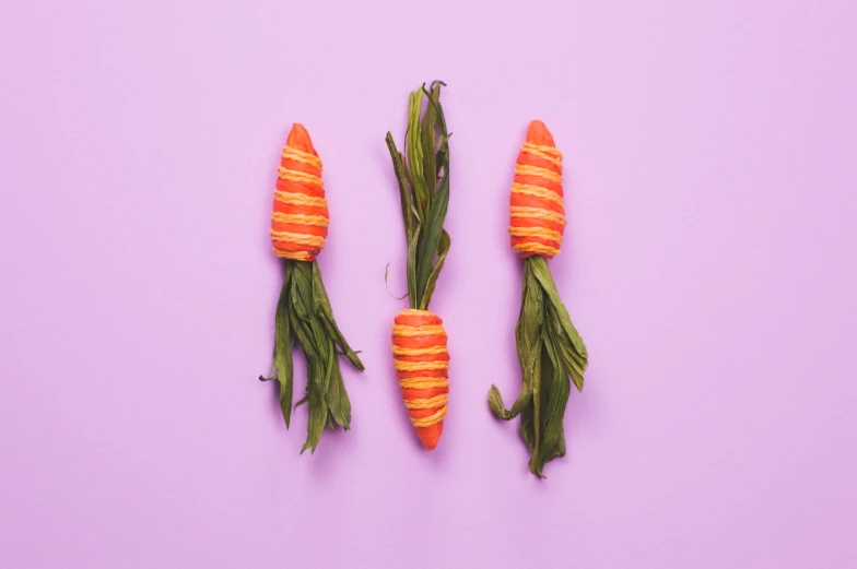 carrots with green leaves are shown on a purple surface