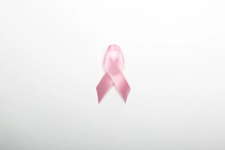a pink ribbon is on the wall next to a pair of scissors