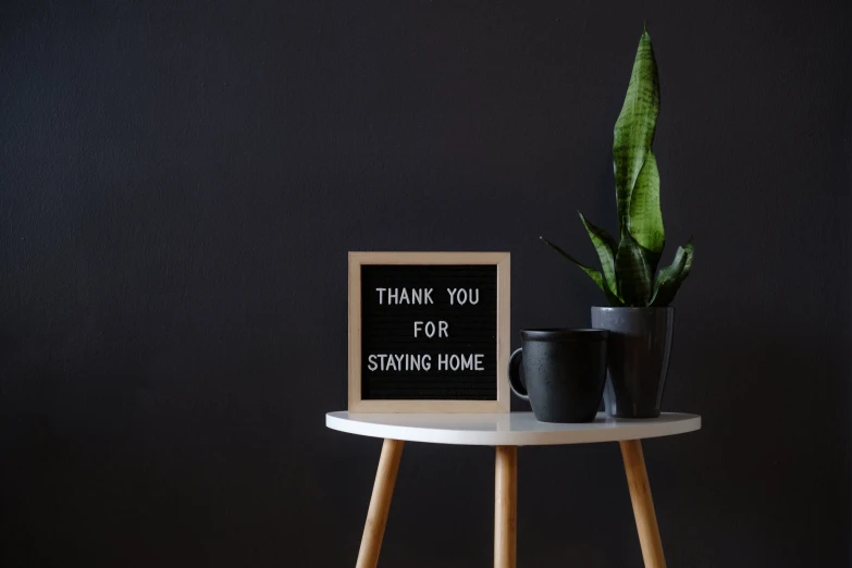 a small table with a vase, cup and sign