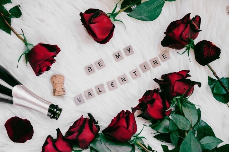 rose petals, wine bottle and a bottle of wine sitting on a white background