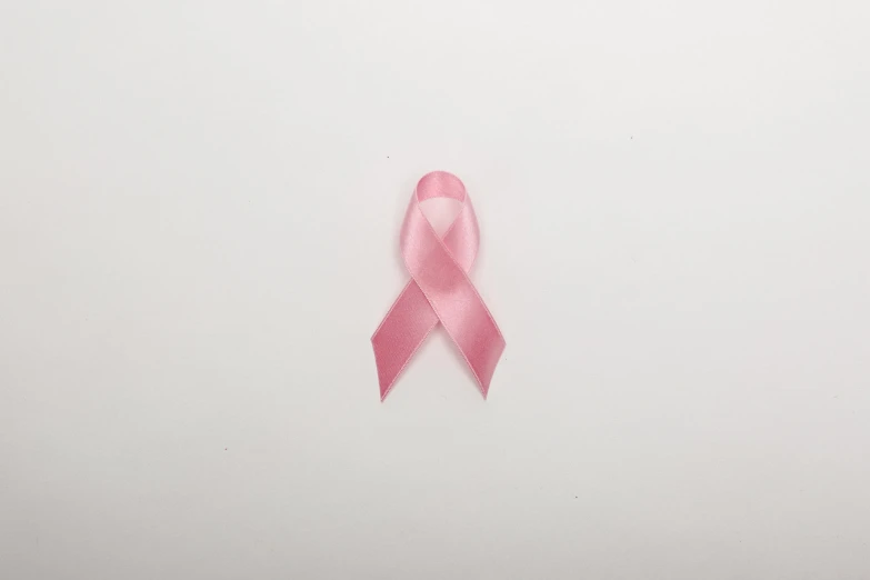 a pink ribbon sits on a white surface