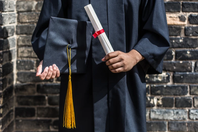 a person holding a graduation diploma and a block of paper