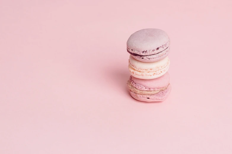 three macaroons sitting on a pink surface