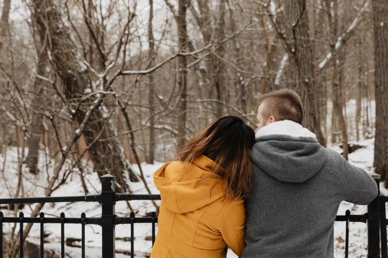 a young man hugs his young wife from behind on a winter day