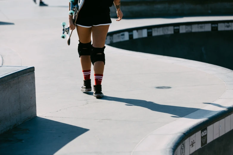 a skateboarder in knee ces carrying her skate board