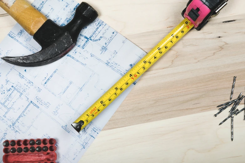 there is a ruler, a hammer, a naildriver and other tools on a table