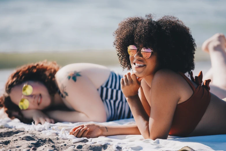 two woman are lying on the beach