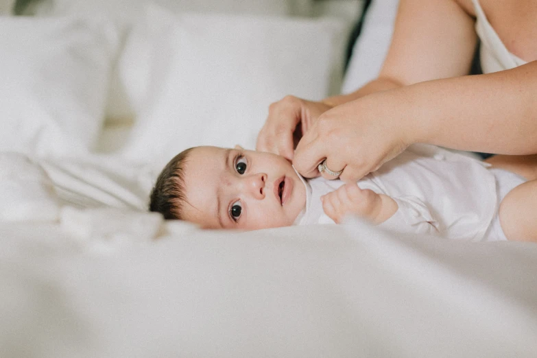 a baby being held up by an adult in bed