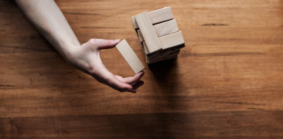 a person holding a piece of brown paper on top of a wooden table