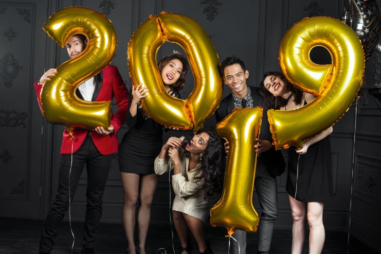 a group of people pose for a po with a large number balloon