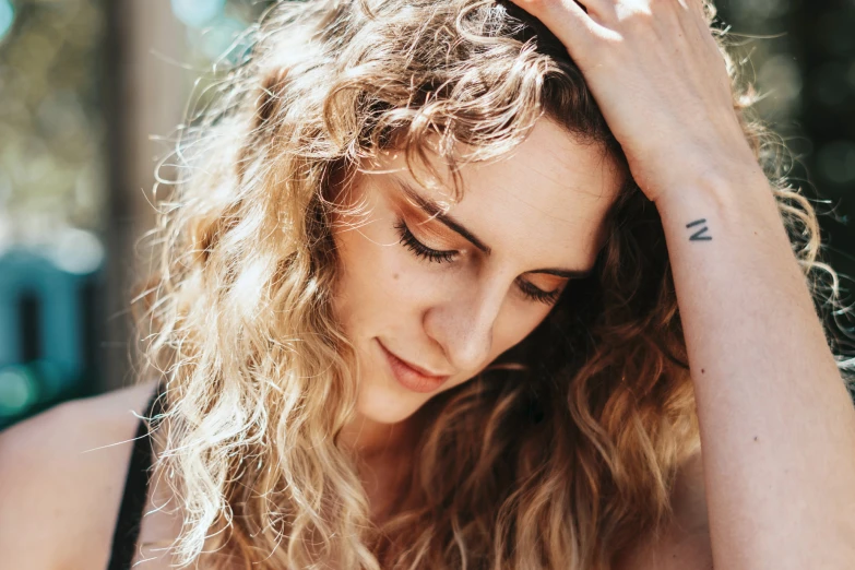 a beautiful blond woman holding her head to her hair