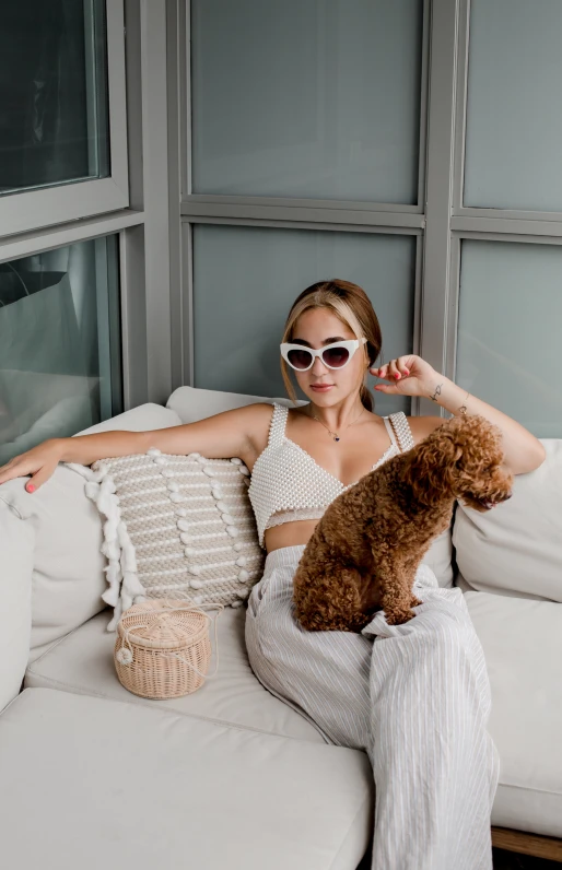 a woman sitting on a white couch holding a dog