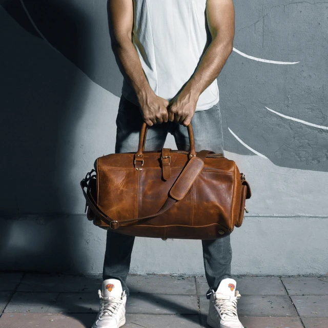 a man holding a brown bag and shoes in front of a wall