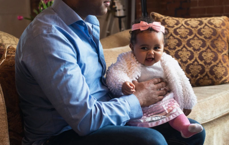 the baby sits on a chair and holds her father