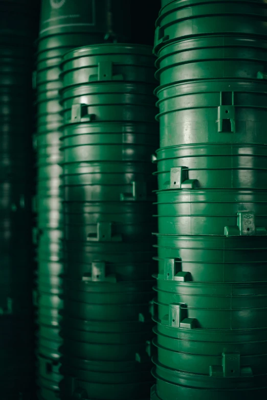 several green stacked large barrels at the back of a building