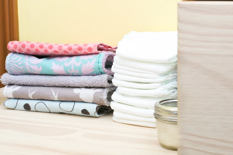 a stack of towels are sitting beside a jar of candle