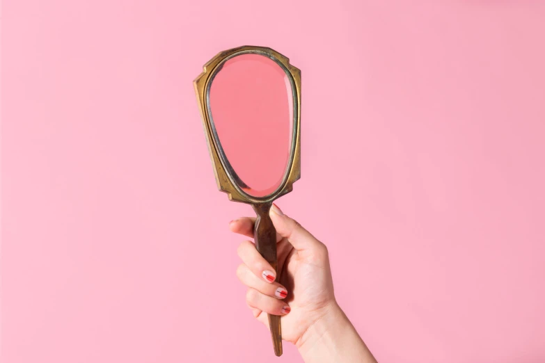 woman's hand holding up a small mirror and keys