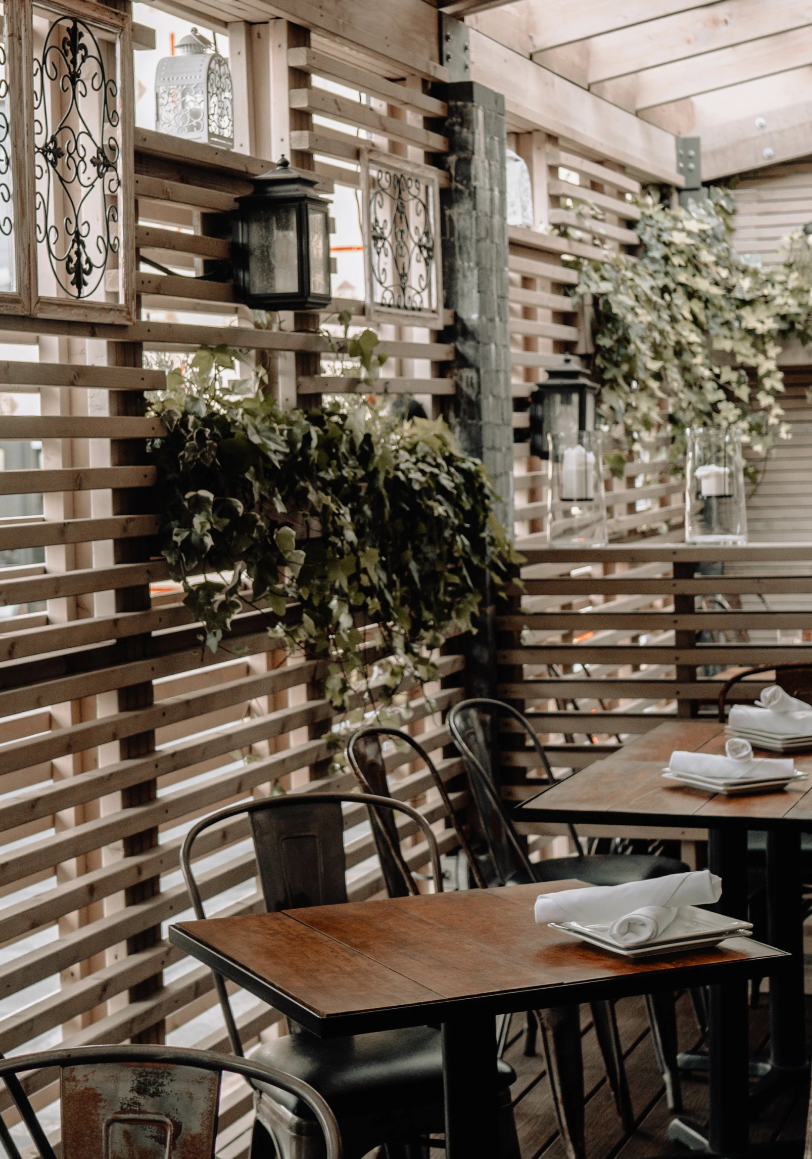 a restaurant with tall wooden windows and hanging plants