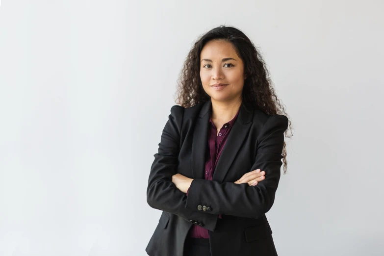 a woman with her arms crossed, in front of white wall