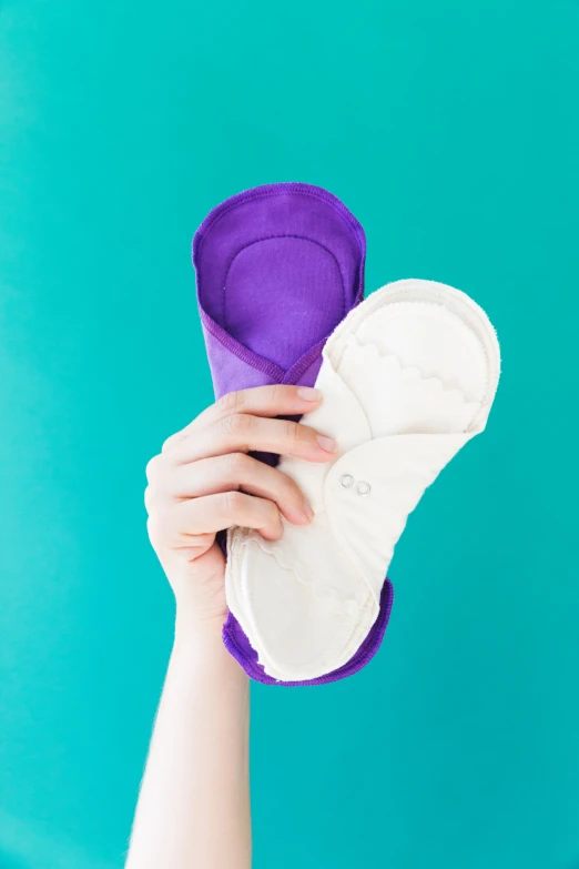 a woman holding onto two pairs of slippers