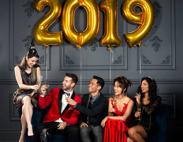 a group of people on couches looking at their cell phones in front of a happy new year sign