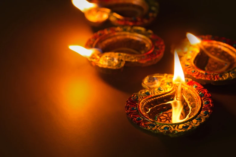 three diyas with lit candles for lighting