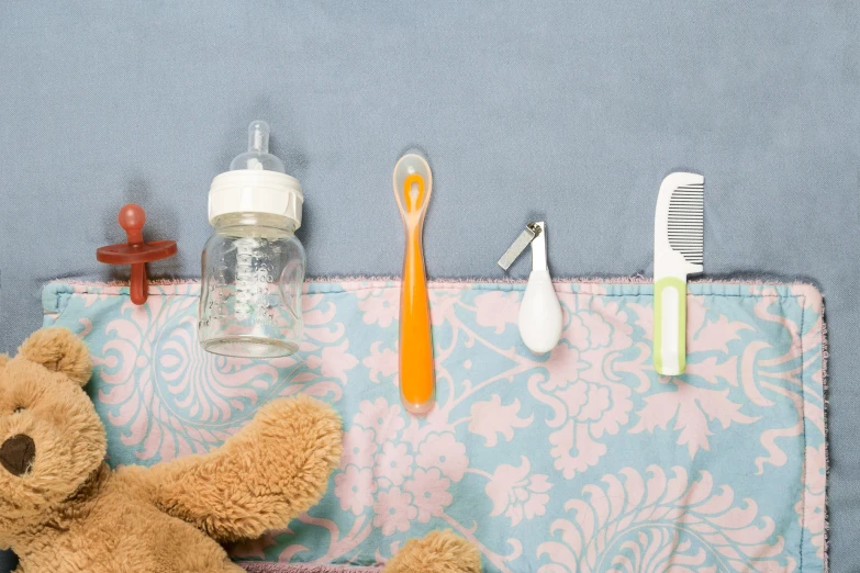 a stuffed bear sitting next to toothbrushes, a toothpaste bottle and a small comb