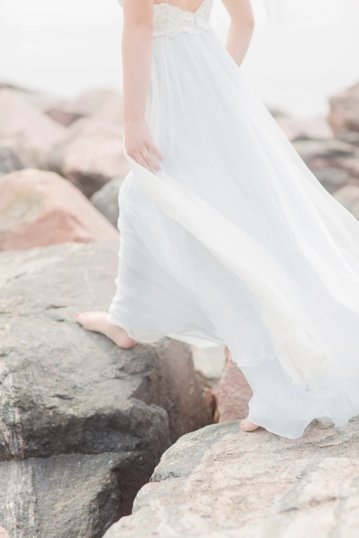 a woman standing on rocks in front of a body of water