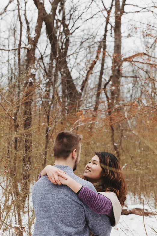 a couple cuddling in the woods in the snow