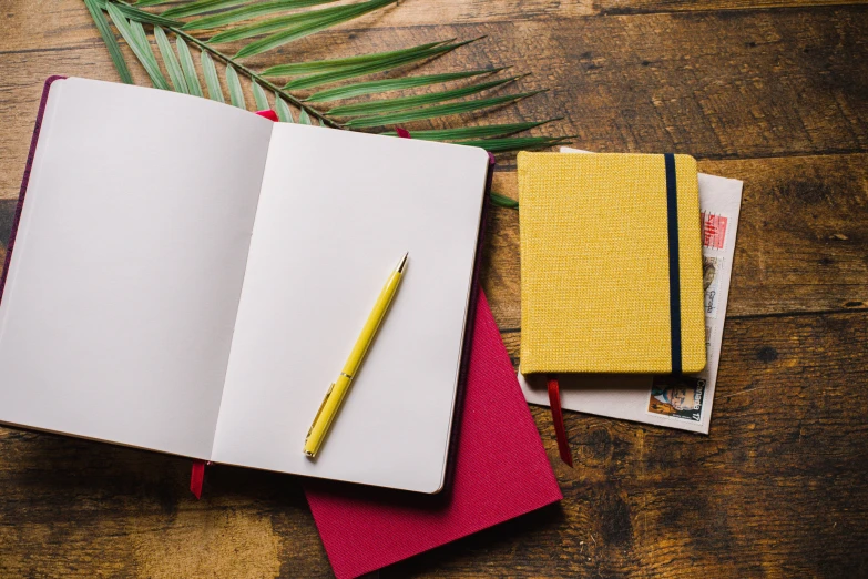 three different books one with notebook, and one with pen