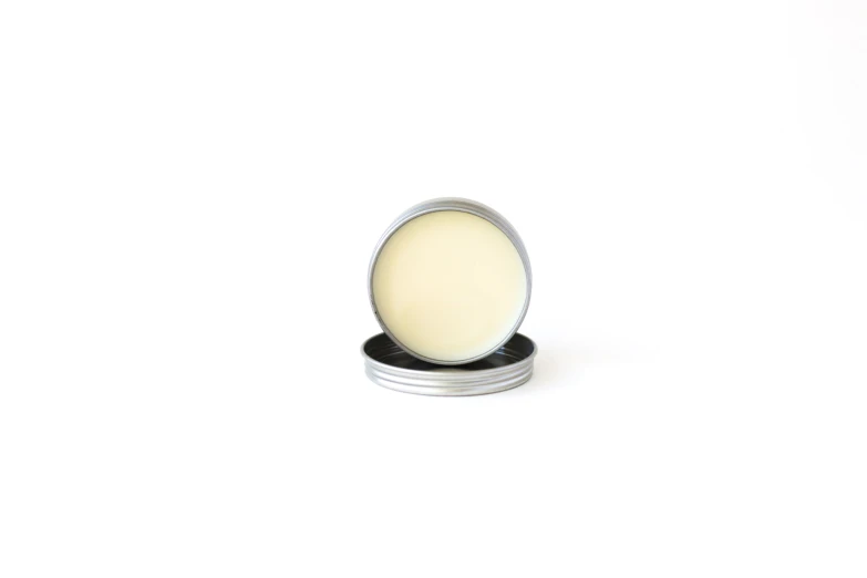 a round metal tin with a white wax and black plastic lid