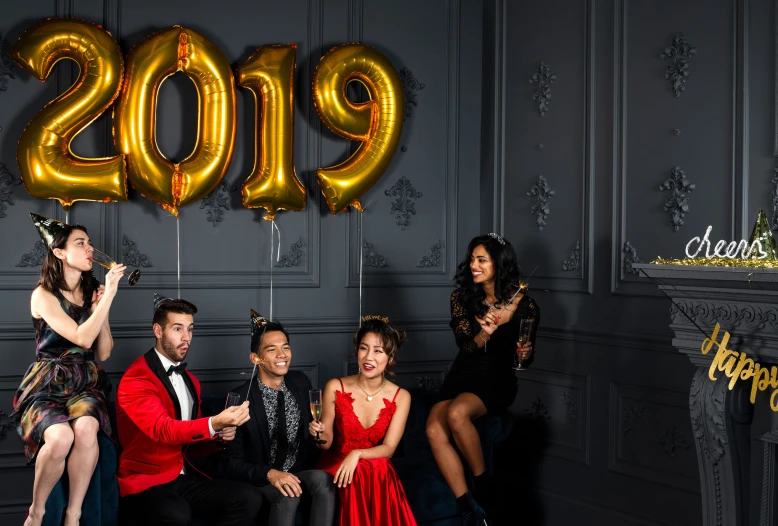 four people are posing in front of the number 2019 on wall